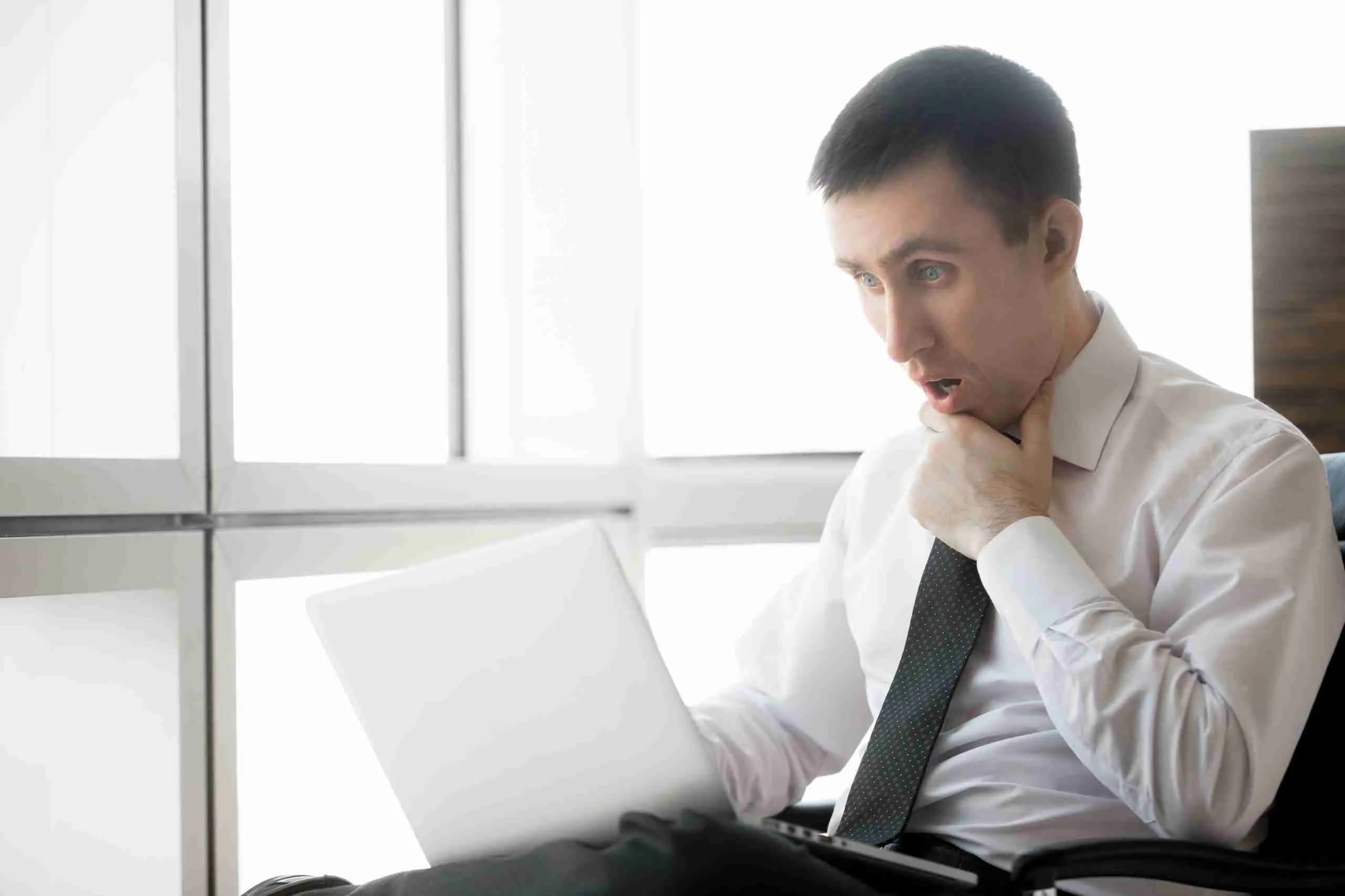 Homme surpris devant un ordinateur, erreurs à éviter en création de site web, conseils NUAWEB, agence web Québec.